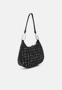Sac à épaule en tweed noir avec quincaillerie en argent, arborant une forme courbée, des accents en cuir et une fermeture zippée. Bandoulière ajustable incluse.