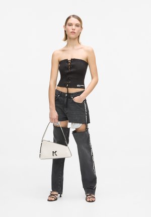 Top corset negru fără bretele, cu detaliu frontal de șireturi; asortat cu pantaloni din denim gri, zdrențuit, și o geantă albă triangulară cu logo.