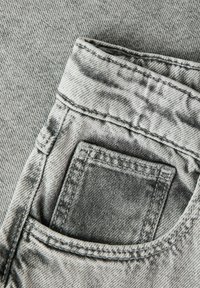 Lähedalt vaadatuna halli denimi pükstetaskut, kus on nähtavad detailne õmblemine ja kangapind.