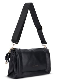 Borsa a spalla in pelle nera con ampia tracolla regolabile in tessuto, accessori in oro e "EXPATRIÉ" impresso sul risvolto anteriore.