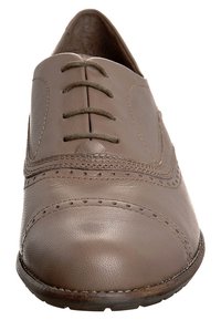 Chaussure en cuir avec une finition lisse et marron. Présente un bout arrondi, six œillets pour lacets et une couture décorative le long des bords.