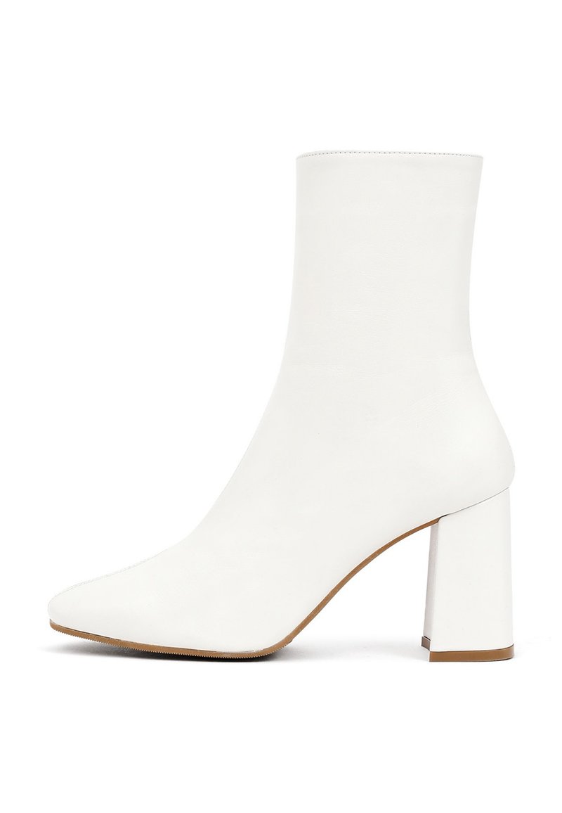 Botte blanche à la cheville en cuir lisse, dotée d'un bout pointu et d'un talon carré épais, avec une texture douce et un design minimaliste.