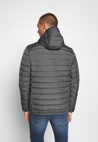 Giacca grigia imbottita con cappuccio, caratterizzata da trapuntatura orizzontale e una texture liscia. Presenta un design semplice e funzionale.