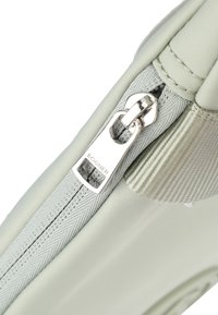 Borsa verde chiaro con finitura testurizzata, dotata di una cerniera argento con "BOGNER" inciso. Tessuto liscio e bordi imbottiti.