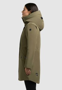 Olivgrüner, isolierter Parka mit Kapuze, ausgestattet mit Reißverschluss und Knopfverschluss, Seitentaschen und Logopatch am Saum. Glatte Oberfläche.