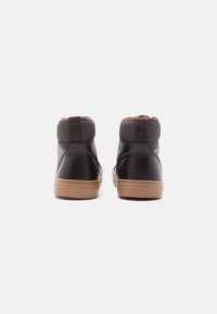 Barna bőr magas szárú tornacipő texturált szürke szövet felsőrésszel és barna műszőrme gallérral, bézs gumi talppal és eltérő varrási mintával.