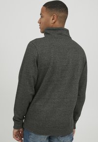 Mørkegrå sweatshirt med høj krave, lange ærmer og struktureret stof. Har ribbede manchetter og nederkant. Bagudsigten vises.