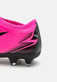 Scarpa da calcio rosa con tomaia testurizzata, accenti neri e un motivo lucido sul tallone. Caratteristiche: quattro tacchetti in plastica nera per la trazione.