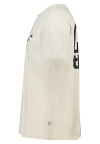 Crème katoenen t-shirt met korte mouwen en een ronde halslijn, met zwart grafisch tekst op de voorkant en een klein merklabel aan de zijkant.