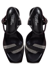 Černé sandály na vysokém podpatku s lesklým povrchem, vybavené křížovými pásky zdobenými st�říbrnými akcenty a čtveratou špičkou.