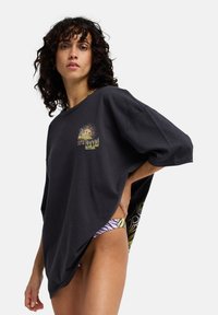 Μαύρο φαρδύ t-shirt από μαλακό βαμβάκι, με γραφικό σχέδιο στο μπροστινό μέρος, κοντά μανίκια και άνετη εφαρμογή για άνεση.