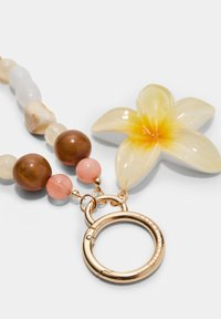Accessoire en perles composé de perles marron, rose et blanche, avec un grand charme en forme de fleur jaune et un fermoir circulaire en or.