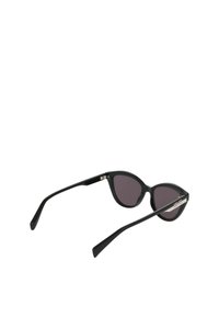 Zwarte cat-eye zonnebril met donkere lenzen, glanzend kunststof frame, slanke veren en een zilveren logo-accent aan de zijkant.