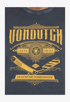Camiseta de color navy con un gráfico amarillo que incluye una navaja recta, espirales decorativas y el texto: "VON DUTCH, AFEITADO LIMPIO, BARBERÍA LEGENDARIA, 1929."