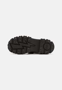 Black rubber sole with a textured, zigzag pattern and raised triangular lugs for traction; rounded toe design; smooth, flat base.
