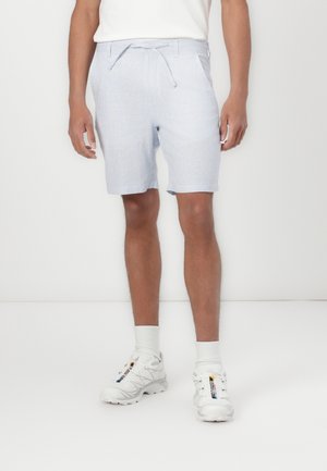 Shorts a righe azzurro chiaro e bianchi con vita con cordino, orlo rifinito e tasche posteriori, abbinati a sneakers bianche e calze corte.
