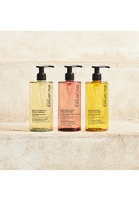 Trois bouteilles de shampooing avec des pompes, disposées en rangée. Couleurs : jaune, rose, vert. Plastique transparent, 400 ml, avec des étiquettes de produit en noir.