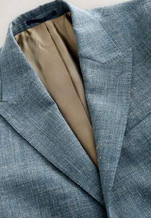 Textured blue blazer with a notched lapel, showcasing a light tan lining and subtle pattern, emphasizing a tailored fit and breathable material.