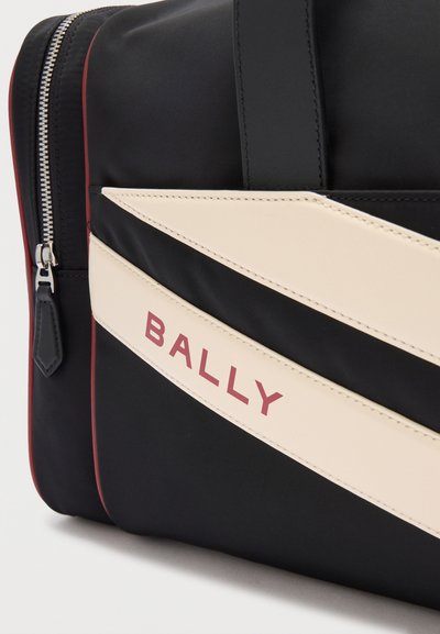 Μαύρη τσάντα Bally με κρεμ διαγώνια ρίγα και κόκκινο λογότυπο, ορατό φερμουάρ και κόκκινες λεπτομέρειες περιγράμματος στο πλάι.