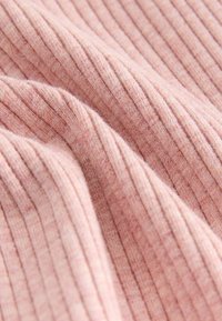 Soft pink ribbed knit fabric with visible texture and gentle folds creating a wavy pattern.