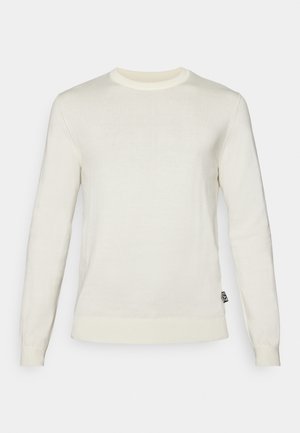 Maglione lungo crema a maniche lunghe con collo tondo, realizzato in materiale a maglia fine, con polsini e orlo a coste e una piccola etichetta logo laterale.
