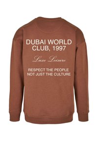 Felpa marrone con collo rotondo. Presenta un testo bianco sul retro: "Dubai World Club, 1997," "Luxe Leisure," e "Rispetta le persone, non solo la cultura."