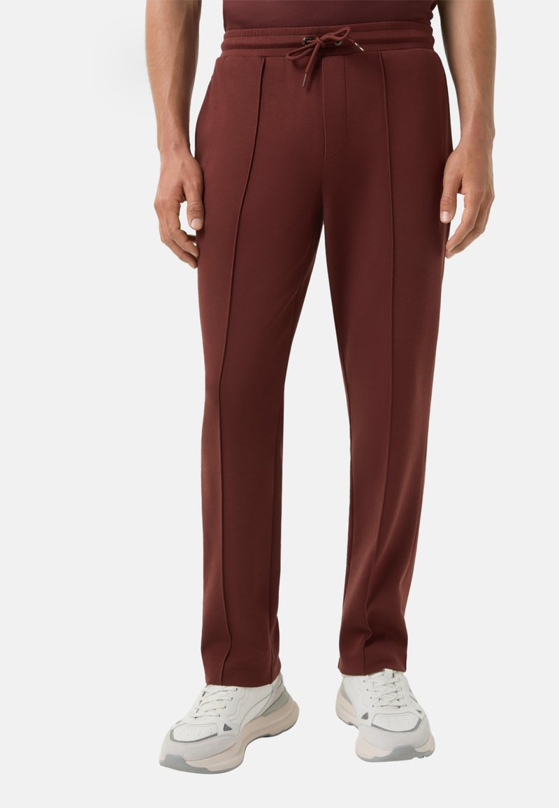 Bordeaux sportieve broek van een zachte stof, met een trekkoord in de taille, zijsplitten en gecombineerd met witte sneakers.