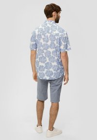 Korte mouwen overhemd in het wit met een blauw bladerenpatroon, gecombineerd met grijze short. Heeft een button-down kraag en lichte stof. Witte sneakers.
