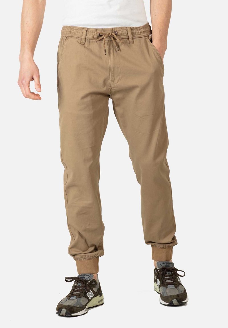 Khaki joggerbroeken gemaakt van zachte stof met een elastische tailleband en boorden; voorzien van zijzakken en een trekkoorddetail.