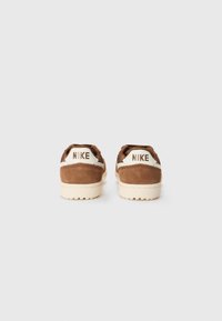 Bruine suède sneakers met crème accenten, voorzien van een dikke witte zool. Logo in het wit gebosst aan de achterkant. Design met een ronde neus.