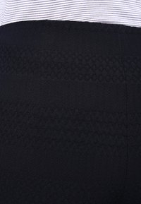 Tmavě modrá texturovaná sukně se zigzagovými vzory, doplněná bílým a černým pruhovaným pasem.