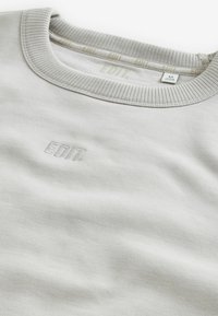 Lys grå sweatshirt med ribbet rund hals, der har en diskret "EDIT." logo i matchende farve. Blød tekstur, afslappet pasform og minimalistisk design.