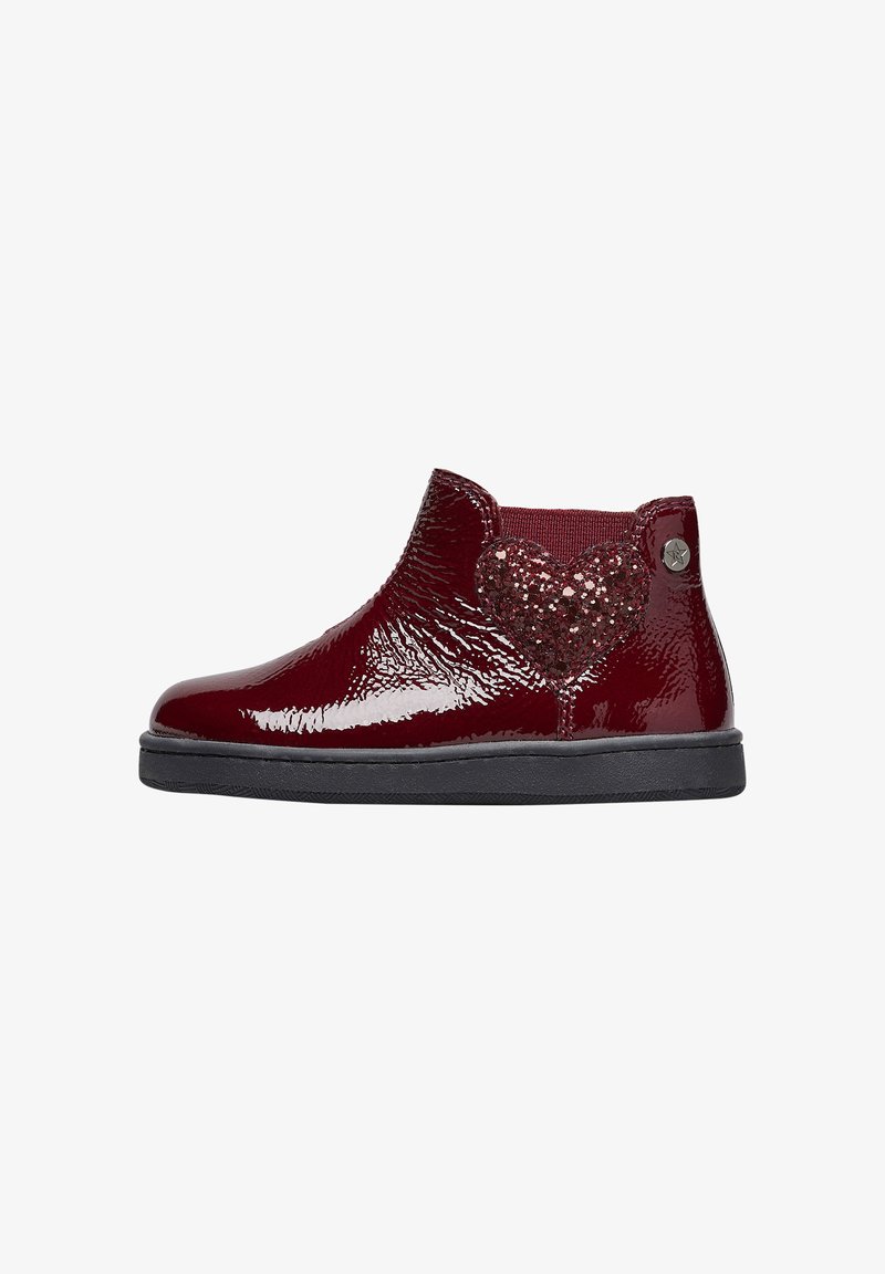 Botín de tobillo brillante de color rojo oscuro con suela negra, decoración de corazón brillante en el costado y pequeño emblema metálico en forma de estrella cerca del talón.