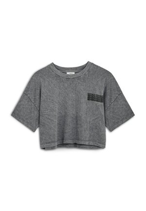 T-shirt gris cropped fabriqué en tissu doux et texturé. Il a des manches courtes et un petit logo en texte noir sur la zone de la poche en haut à gauche.