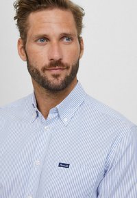 Overhemd met knopen in blauw-witte strepen, gemaakt van katoen. Beschikt over een klassieke kraag, een borstzak en een merklabel op de zak.