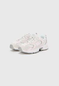 Pari valkoisia ja vaaleanpunaisia juoksukenkiä, joissa on harmaat pohjat ja verkkokankaiset osat, aseteltuna vierekkäin valkoisella taustalla.