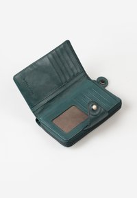 Portafoglio in pelle teal con chiusura a zip, sei scomparti per carte e una finestra trasparente per l'ID. Texture liscia con rivestimento a contrasto e chiusura a scatto.