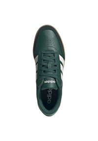 Sneaker verde in pelle con strisce bianche, design con lacci, superficie testurizzata e suola in gomma marrone; presenta il marchio "adidas" sulla linguetta.