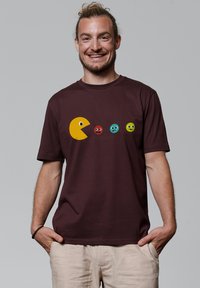 Bordeaux crew-neck T-shirt met een gele pixelachtige figuur en kleurrijke ronde gezichten gedrukt aan de voorkant. Katoenen stof, korte mouwen.