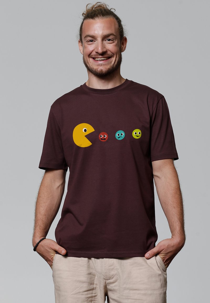 Bordeaux crew-neck T-shirt met een gele pixelachtige figuur en kleurrijke ronde gezichten gedrukt aan de voorkant. Katoenen stof, korte mouwen.