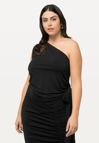 Vestido negro de un solo hombro hecho de tejido elástico, con fruncido lateral y un detalle de nudo en la cintura para un aspecto y ajuste gathered.