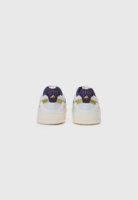 Lila och vita sneakers med mesh- och lädermaterial. Har en texturerad häl, gula detaljer och logotyp på baksidan.
