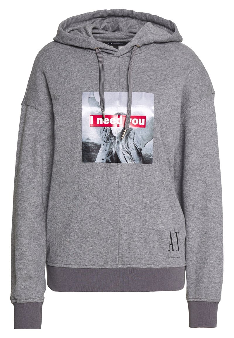 Sweat à capuche gris avec photo sur le devant d'une personne levant les bras et texte rouge "J'ai besoin de toi" ; logo AX Armani Exchange près de l'ourlet.