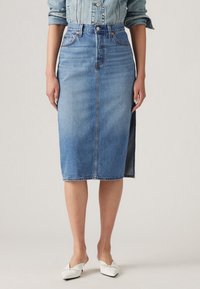 Midihame denim vaaleansinisena, jossa on edessä halkio ja rouhea helma. Yhdistetty valkoisiin kärkitossuihin ja sopivaan denim takkiin.