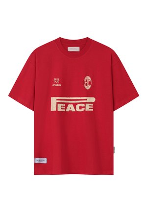 Červené tričko s krátkym rukávom s béžovým textom "PEACE", vyšitým logom "another" a emblémom ACL 2023 na prednej strane.