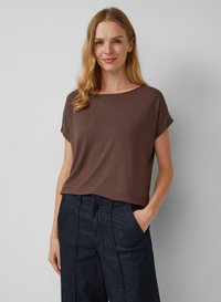 Bruine T-shirt met korte mouwen, gemaakt van zachte stof, met een ronde halslijn en een relaxte pasvorm, gecombineerd met donkerblauwe high-waisted broek.