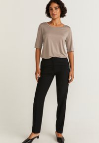 Vaaleanharmaa lyhythihainen paita yhdistettynä mustiin kapeisiin housuihin. Paidassa on leveä kaula-aukko; sileä kangas; kengät ovat mustat ballerinat.