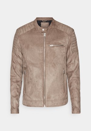 Hnedá semišová bunda s stojáčikovým golierom, zipsovým zapínaním a prešívanými ramenami. Obsahuje predné vrecko na zips a bočné vrecká na zips.