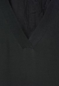 Tela negra con un diseño de escote en V. Textura suave, con costuras sutiles a lo largo del escote. Estilo simple y versátil.