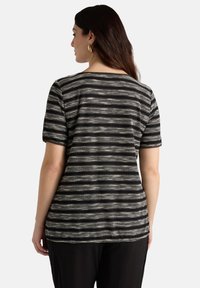 Top de manga corta a rayas en blanco y negro con un corte relajado y escote redondeado; presenta un patrón de rayas alternando entre delgadas y gruesas.